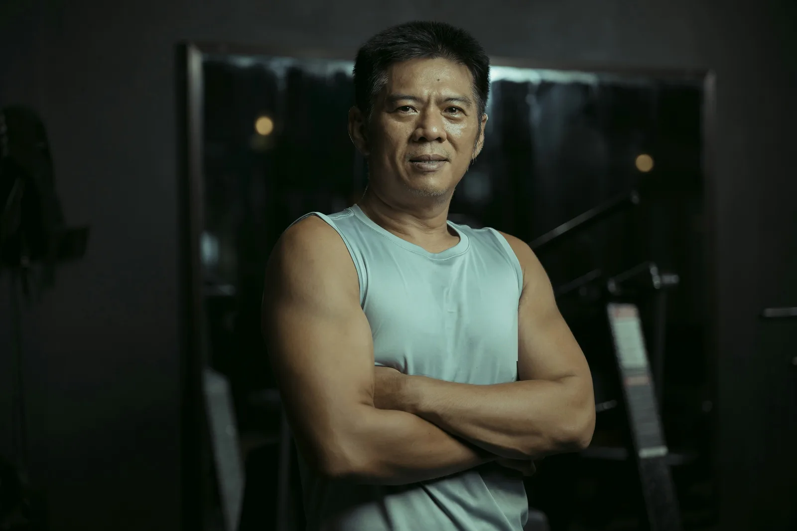 Fit man standing with his arms crossed in a gym